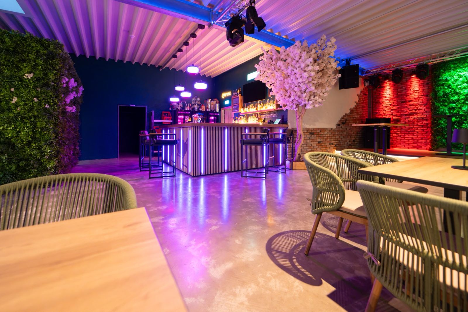 Beleuchtete Bar mit Kirschblütenbaum und Loungetischen