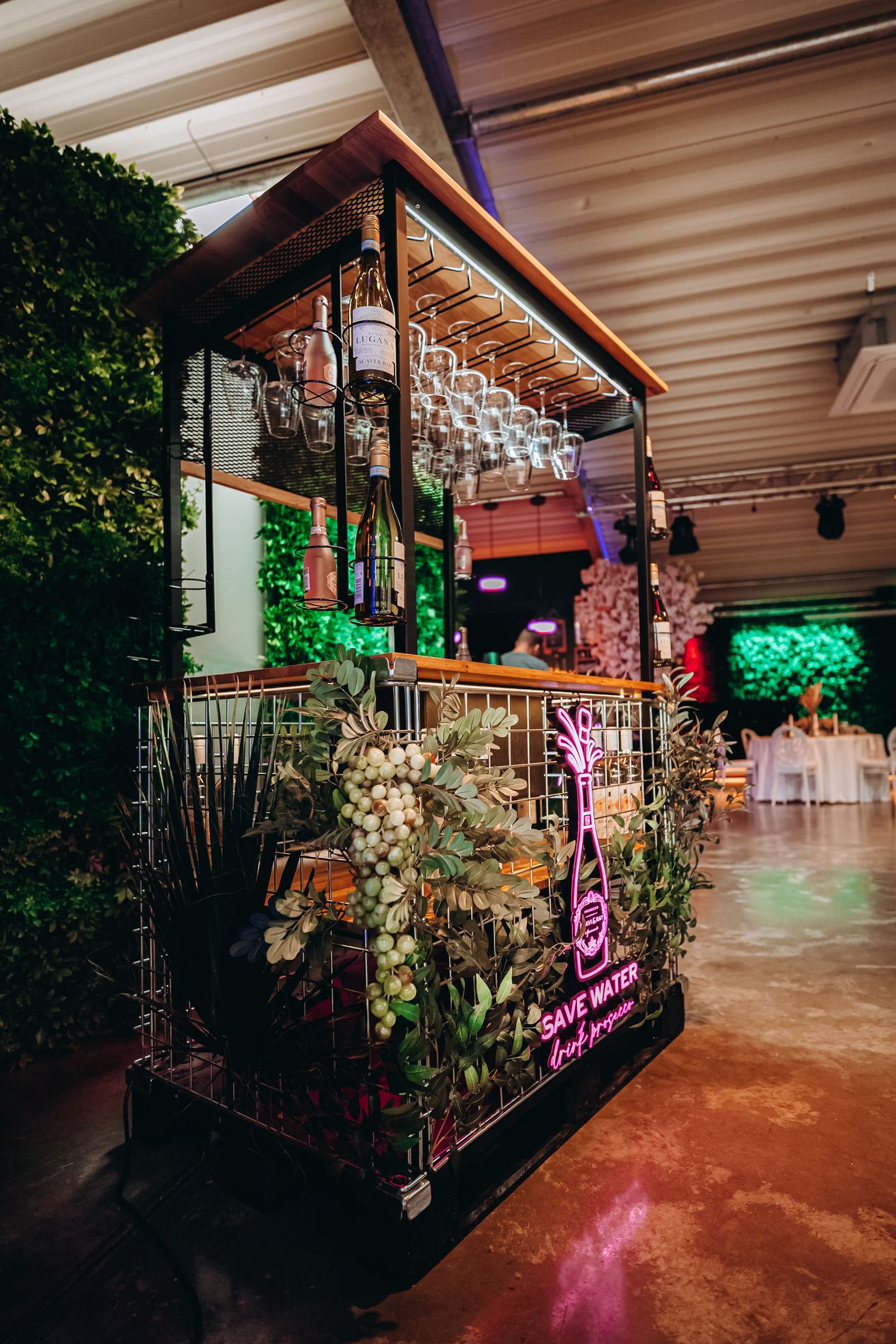 Begrünte Bar mit Neonschriftzug bei einem Firmenevent