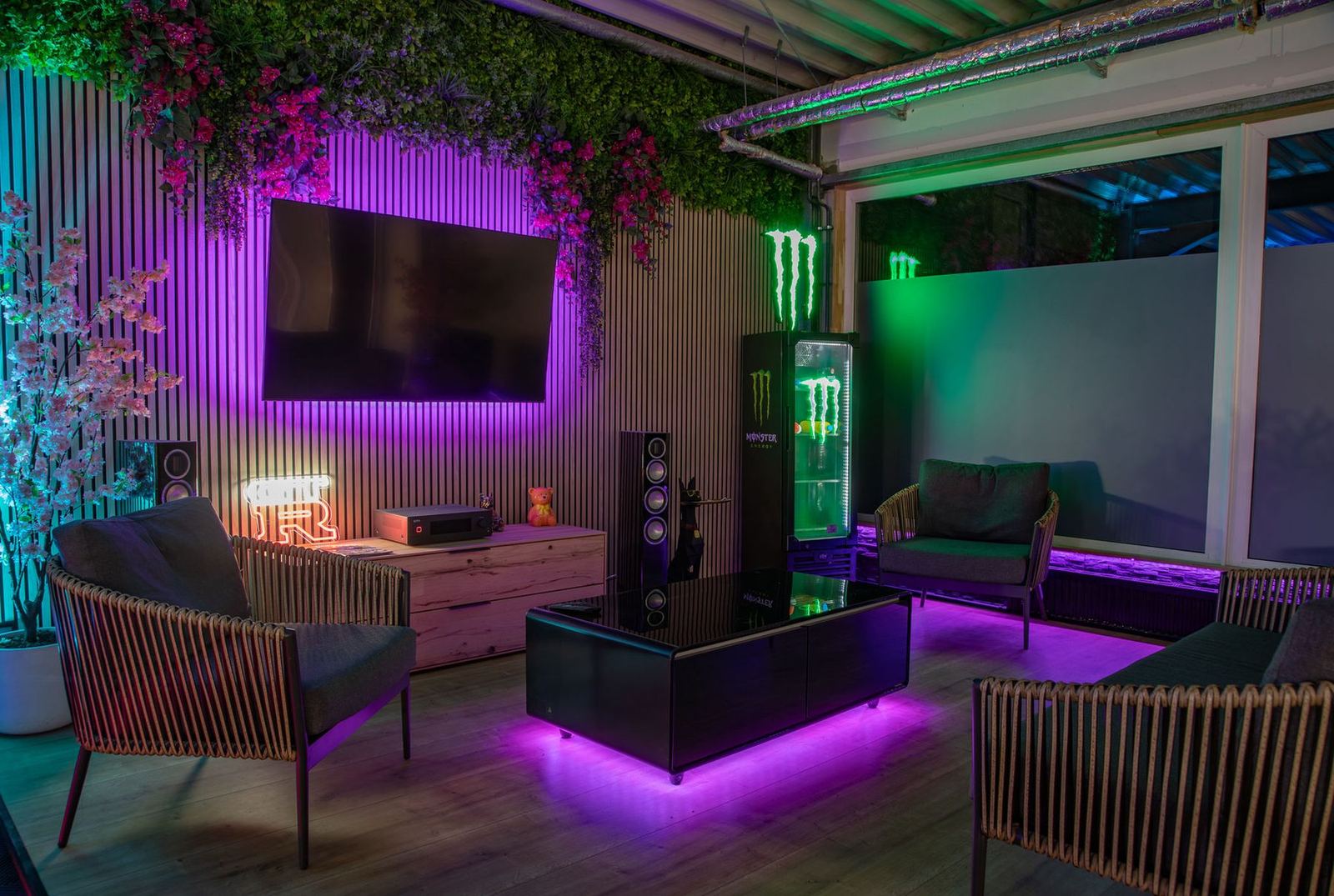 Lounge mit Sofas, Großbildschirm und Pflanzenwand