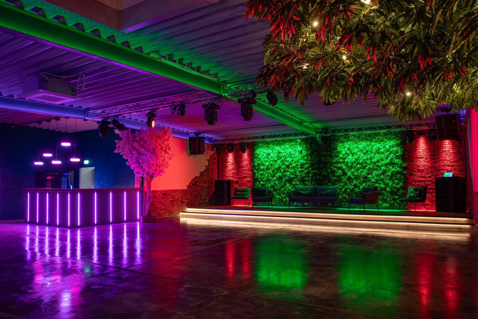 Großer Saal mit beleuchteter Bar und begrünter Wand